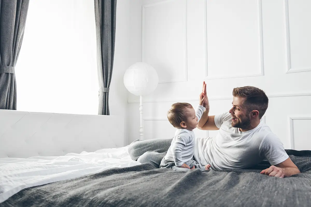 Father and child giving each other high five on a bed