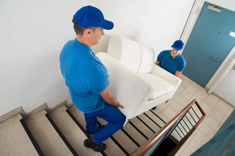 Two movers carrying sofa up a staircase