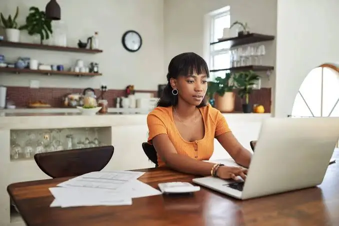 A woman reviewing her purchase paperwork on a laptop at home