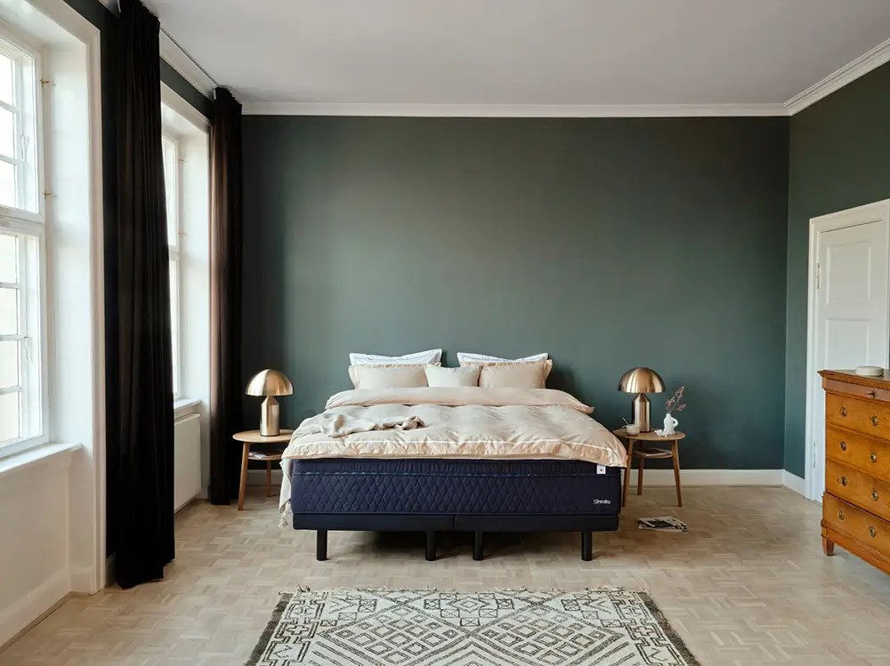 A neatly made bed with a Stressless mattress and bedding in a bright bedroom