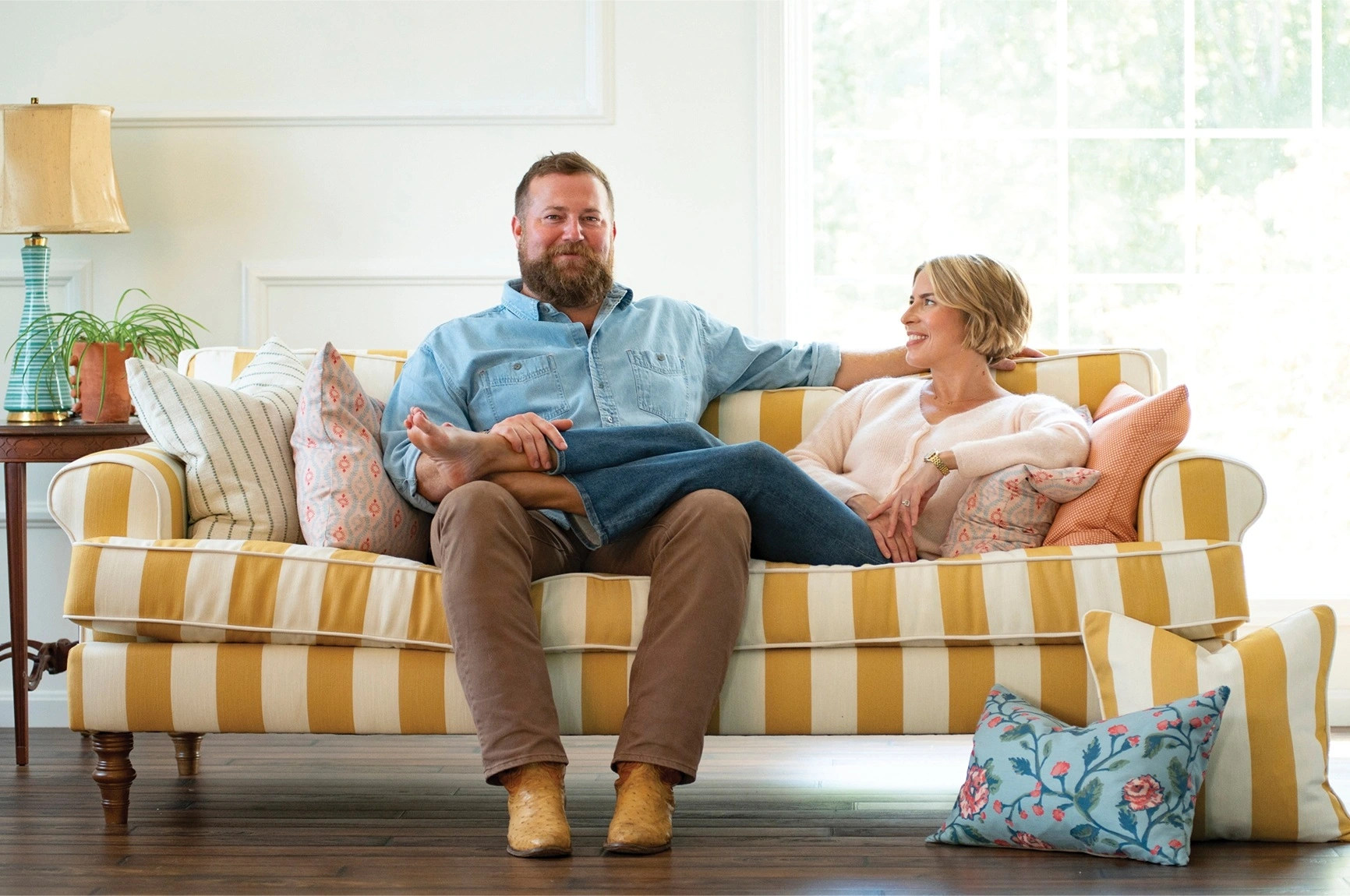 Erin and Ben Napier relaxing on a yellow striped Best Home Furnishings sofa