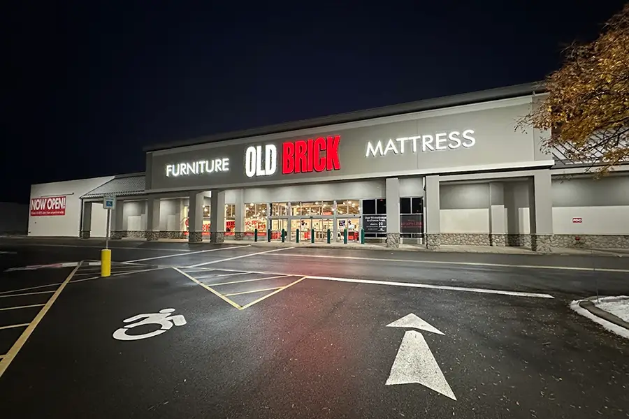 The Old Brick Furniture & Mattress storefront in Henrietta, lit up at night